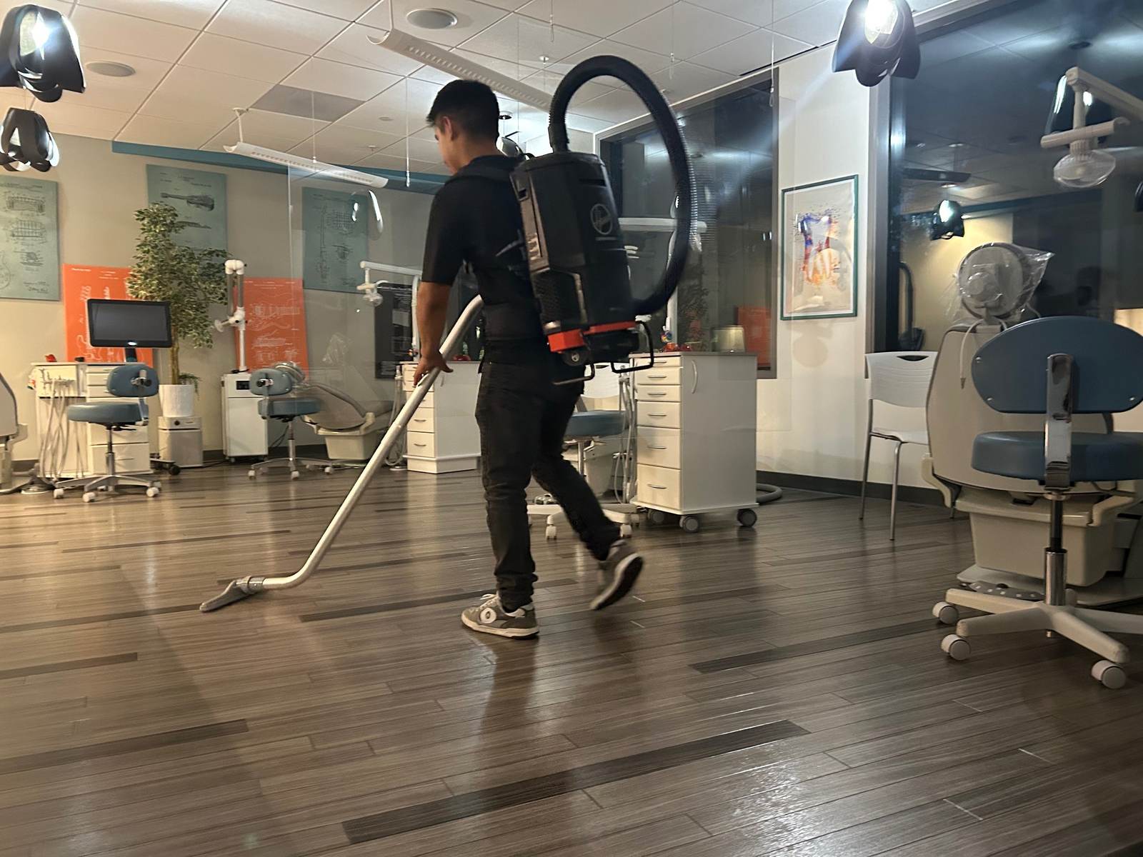 KCS crew member vacuuming a dental clinic with a backpack vacuum at night