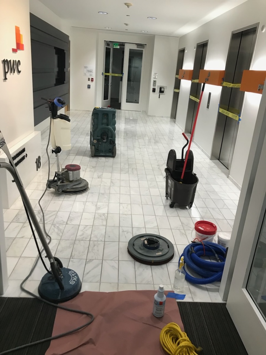 Floor machines and equipment staged on a marble corridor during a maintenance night